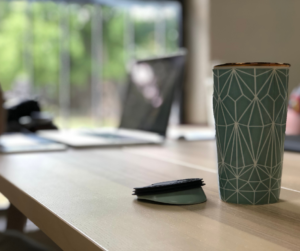 Coffee cup with laptop in the background